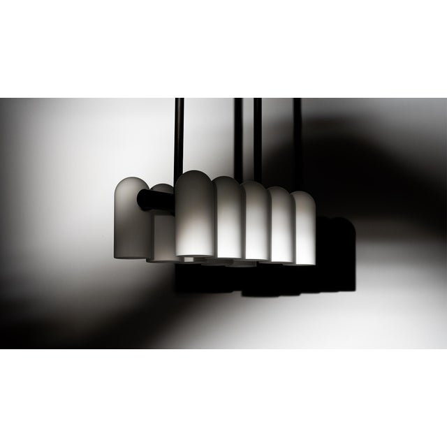 A colonnade of light sources. This delicate engine of frosted glass generates a luminous environment while contrasting...