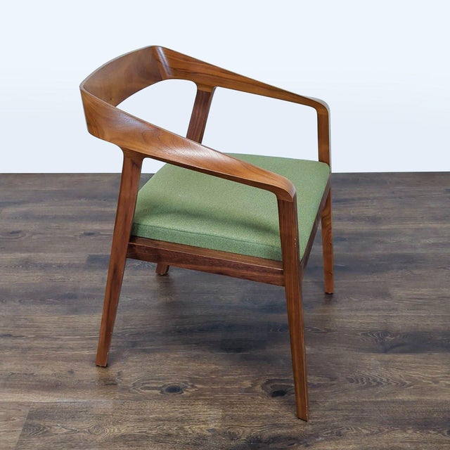 This stylish chair features a smooth walnut wood frame and a comfortable green cushioned seat. Its curved backrest and arm...