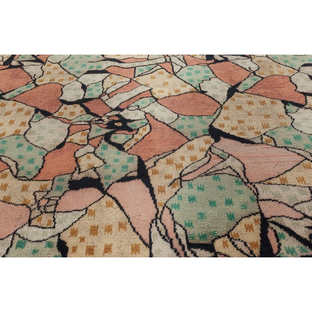 This remarkable vintage rug, crafted in Europe during the 1950s, is a vivid testament to mid-century modernist...