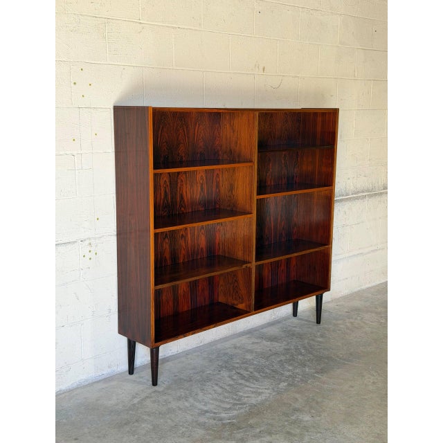 This spacious bookcase features a clean-lined rectangular profile resting on tapered legs. The expansive open face...