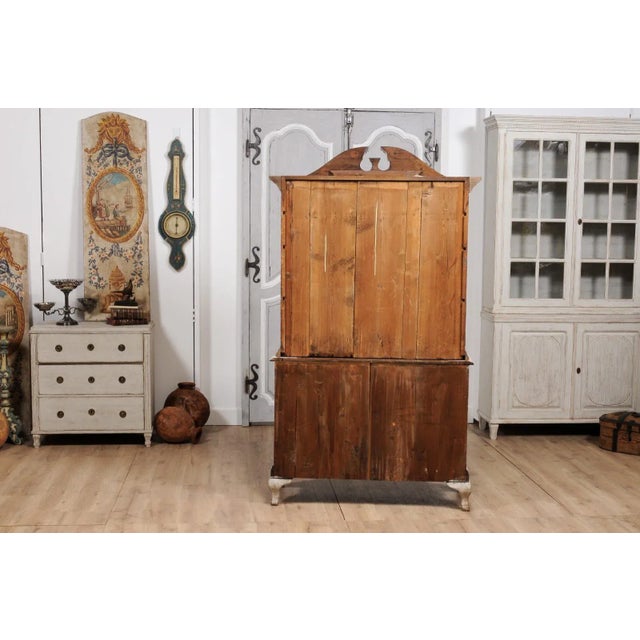 A Swedish Rococo style rich light grey painted vitrine cabinet from circa 1850 with bonnet top pediment, glass doors, four...