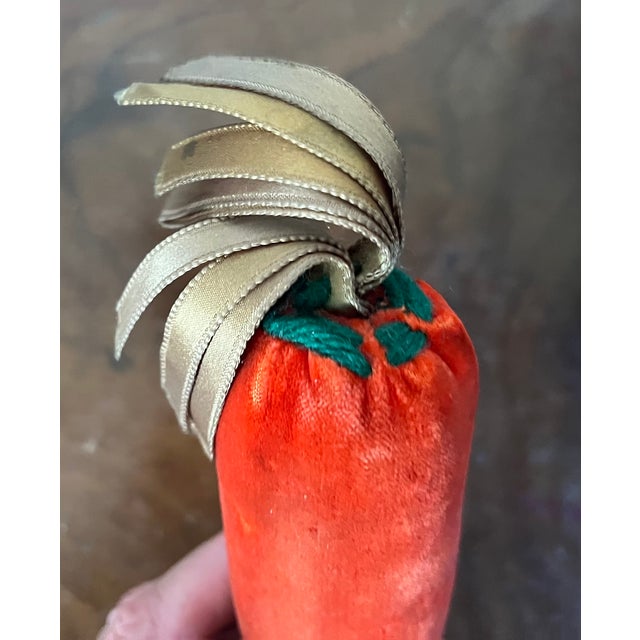 Orange velvet soft sculpture or pin cushion in the form of a carrot with green silk ribbon top. Measures 8" long x 1 3/4"...