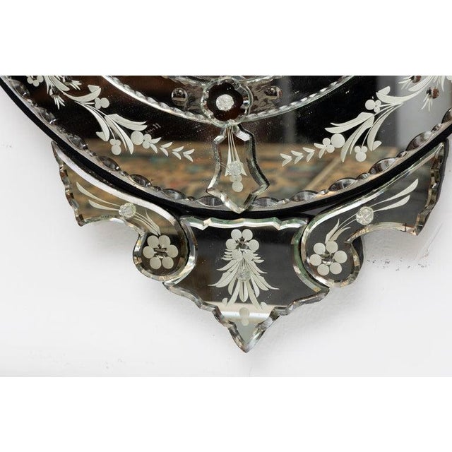This is an elegant Venetian mirror featuring a gracefully shaped oval central plate surrounded by finely etched mirrored...