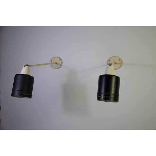 A striking pair of mid-century modern adjustable metal wall lamps, produced in germany in the 1950s. The lamps feature a...