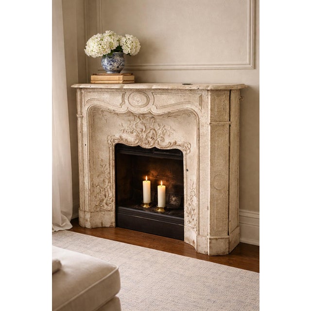 A substantial antique French fireplace surround cast in iron and finished in a weathered faux-limestone paint treatment,...