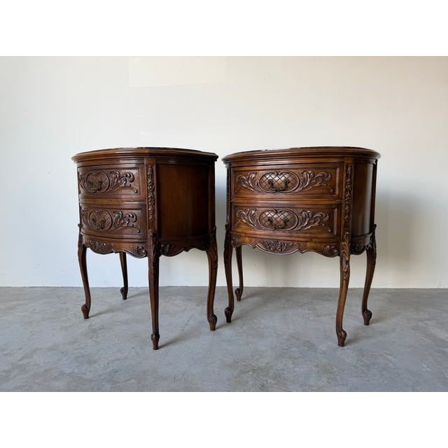 Elegant pair of French Rococo–style demilune side table cabinets, finely crafted in carved walnut and topped with striking...