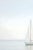 Minimalist coastal artwork featuring a solitary sailboat on calm water beneath a soft, neutral sky. The composition...