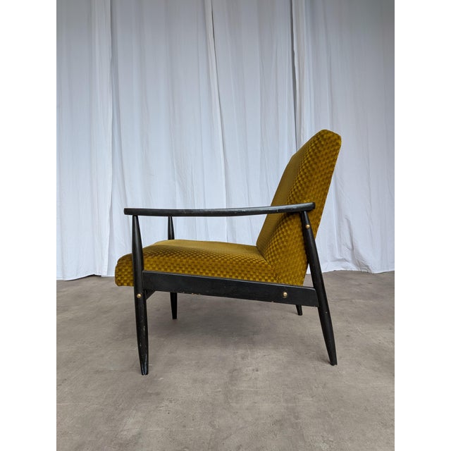 Vintage mid-century armchair made in Yugoslavia in the 1960s. The chair features a solid wooden base and yellow...