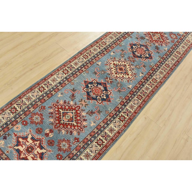 A tribal Caucasian Kazak runner hand-knotted with fine wool on a cotton foundation. This rug features a row of geometric...