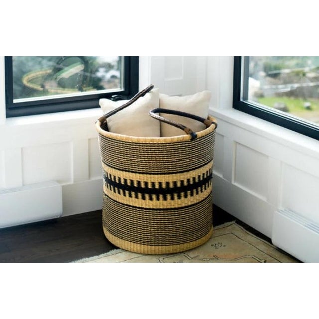 Tall hamper with leather handles Designed by us and hand woven in northern Ghana in the Bolgatanga Region by traditional...