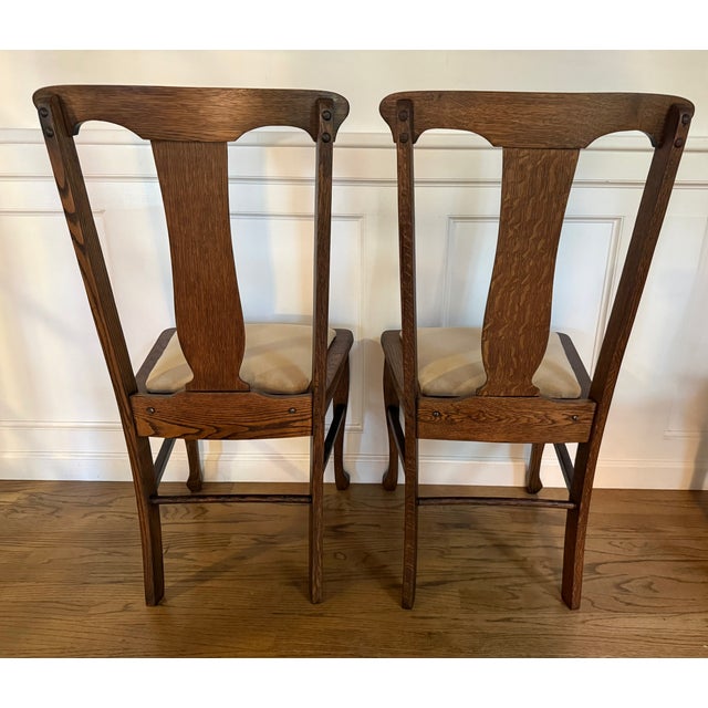 Beautiful pair of vintage oak dining chairs, professionally refinished by Hilaire Furniture. These chairs feature...