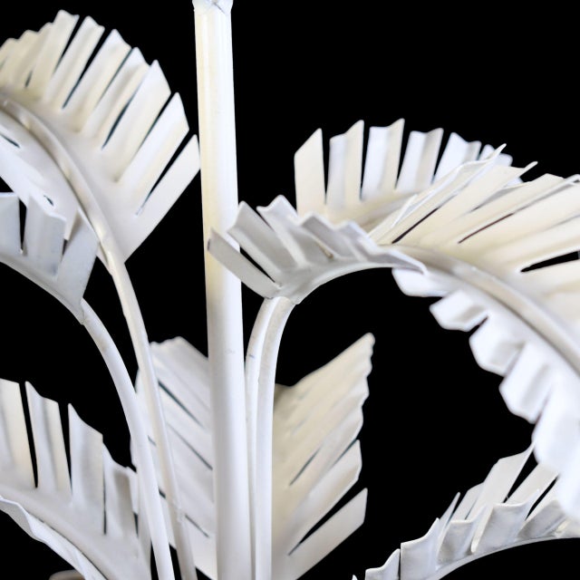 A petite white chandelier dripping with faux bamboo leaves — a jewel of a light fixture for a powder room, breakfast nook,...