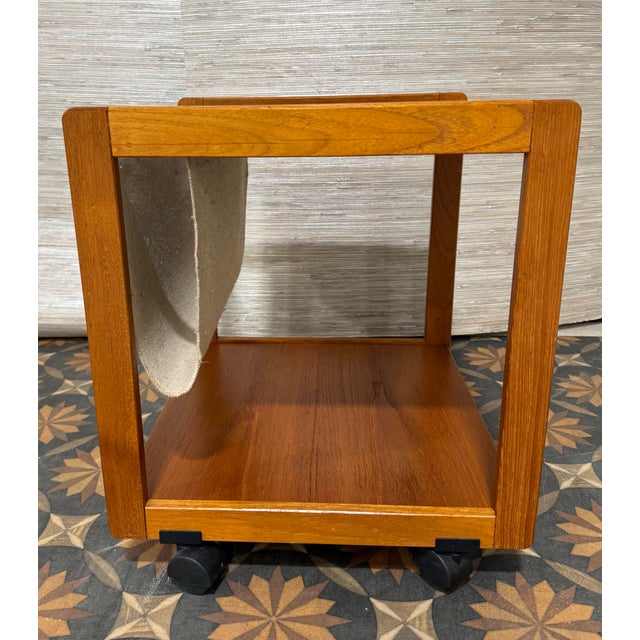 Sleek and functional mid-century modern side table featuring a minimalist open-frame design and integrated magazine sling....