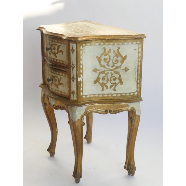 An Italian chest of drawers with white and golden details. The vintage Florentine chest has two drawers that open with...