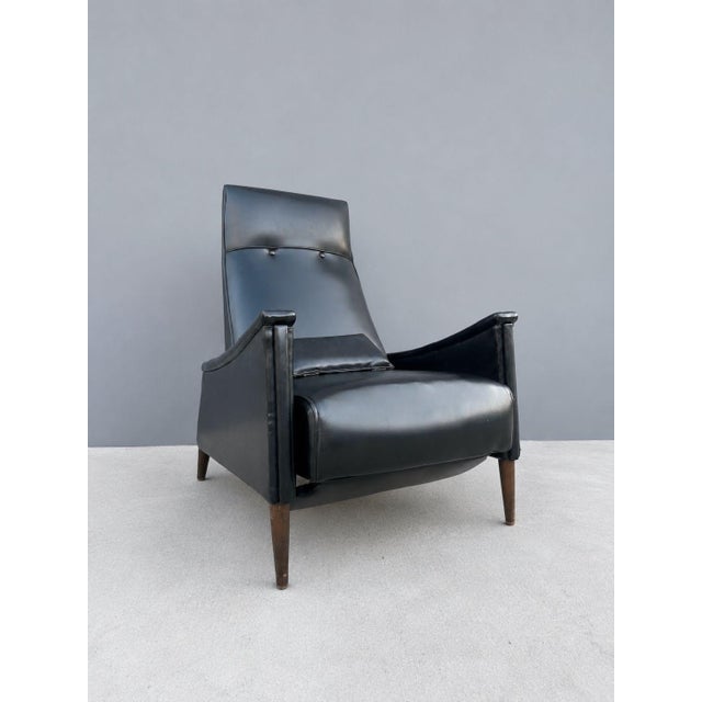 A sleek mid-century modern reclining lounge chair with black upholstered body, gently sloped high back, curved arms, and...