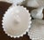 Vintage pair of large milk glass covered fruit bowls with an overall sawtooth design. Each bowl raised on a tall stem....
