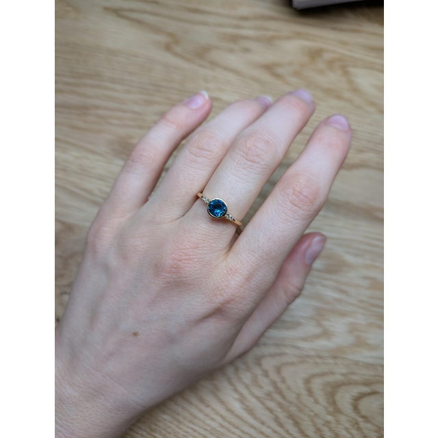 This ring is a breathtaking piece of jewelry that showcases the vibrant allure of a 0.80ct London Topaz set in luxurious...