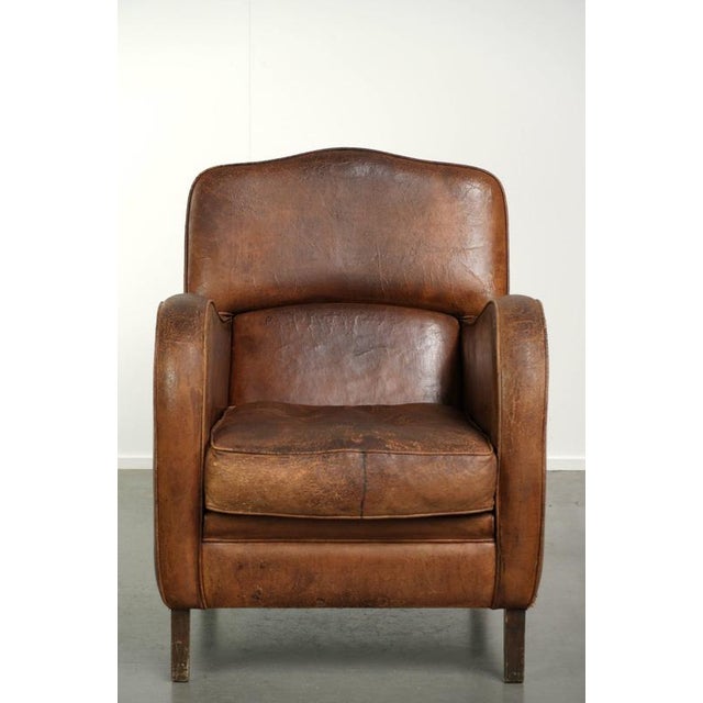This comfortable vintage armchair is made of sheepskin and has a rugged look. Additionally, this armchair features a dark...