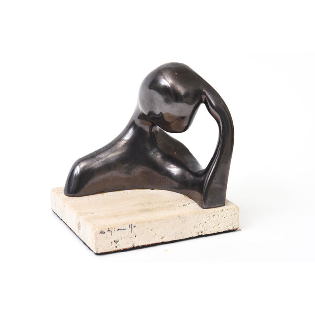 This signed small intimate mixed media sculpture is a graphite bronzed metal finish over ceramic that sits on a travertine...