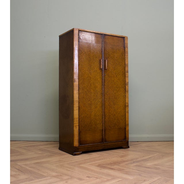 A 1930s Art Deco compact wardrobe in figured oak veneer with contrasting walnut trim, original handles, a pull-out rail...