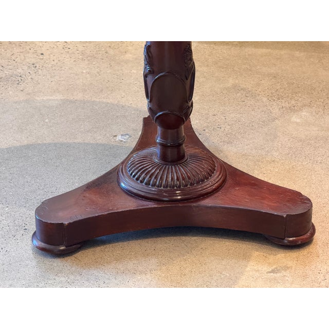 English mahogany side table with a circular dished top raised on a turned and tapering pedestal carved with foliate...