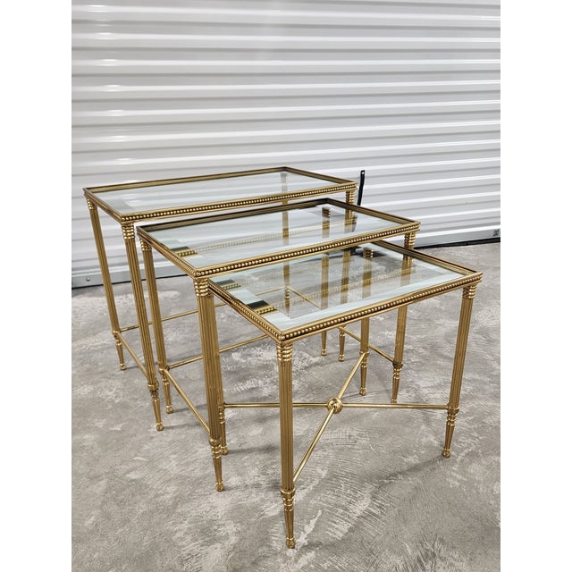 Gorgeous set of Italian Regency style nesting tables with silvered mirrored borders glass top and brass ball trims. The...