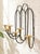 A wonderfully sculptural vintage wall-mounted candle holder combining looping black metalwork with warm brass candle cups....