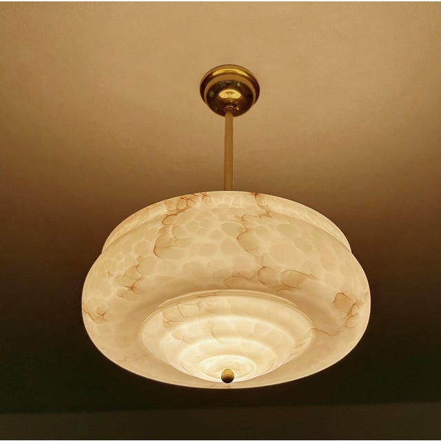 Art Deco pendant lamp from the 1930s, stepped pink mottled marble glass shade with darker streaks mounted on a bronze...