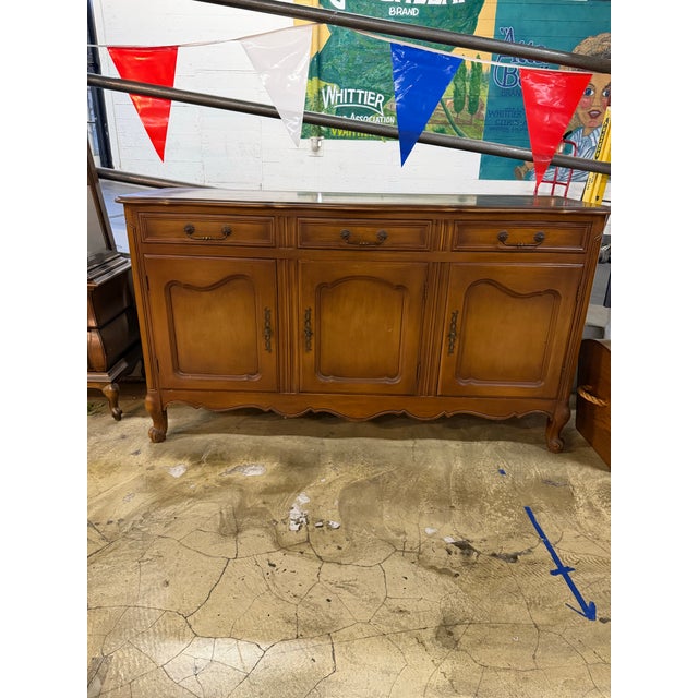 Elegant French Provincial buffet featuring three drawers, paneled cabinet doors, cabriole legs, and decorative brass...