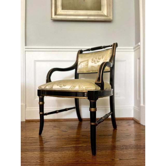 These vintage black lacquer Regency-style chairs feature elegant rounded arms and gold detailing on arms, back, and...