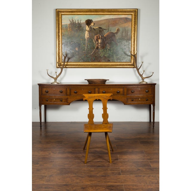 An English oak hall chair from the mid-19th century, with pierced back, carved letters and wooden seat. Created in England...