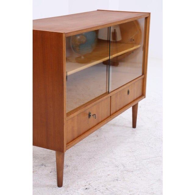 Vintage 1960s chest of drawers with glass sliding doors and two spacious drawers. The successful combination of display...