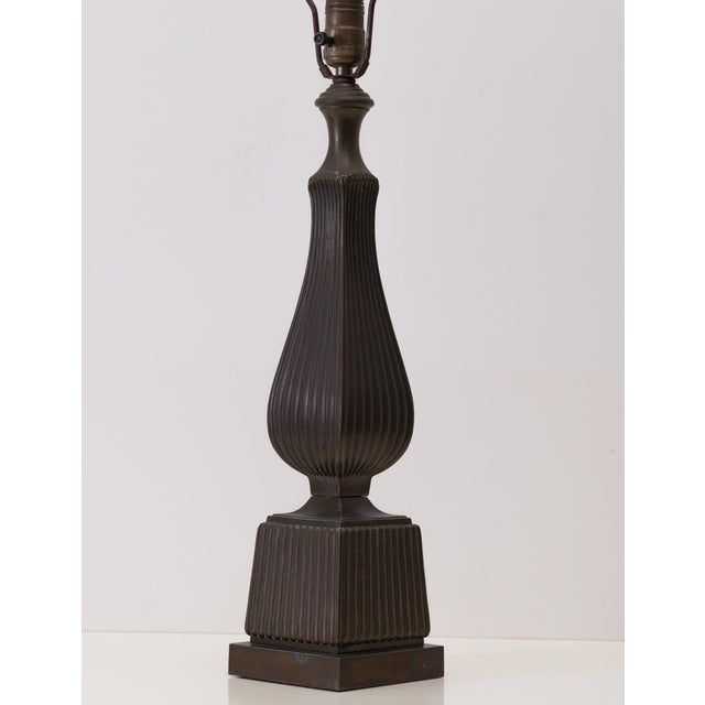 Stately deep bronze tone table lamp featuring a sinuous column shape atop a square base. Note the allover ribbed detail,...