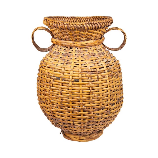 This substantial rattan basket takes its shape from a classical amphora — a full, rounded body tapering to a flared rim,...