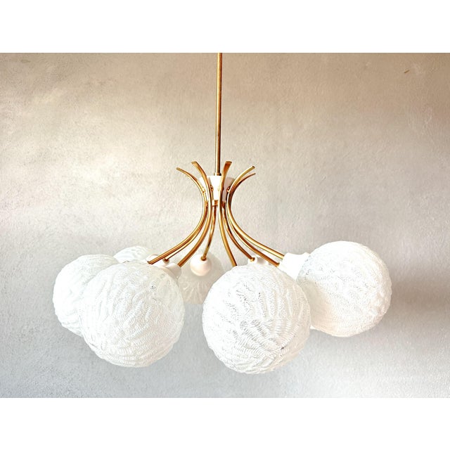 Beautiful mid - Century design. 1970s sputnik chandelier. Brass base with 8 curved arms from which white sculpted thick-...