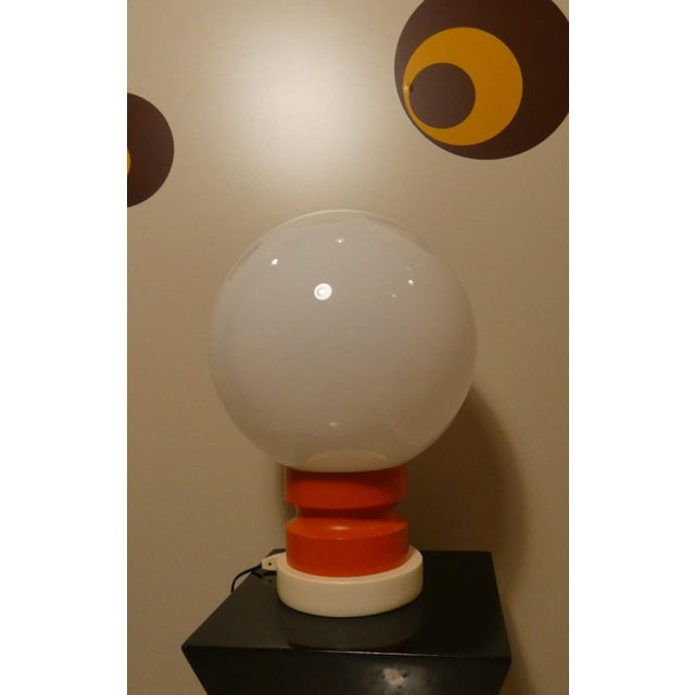 1970s table lamp featuring a large, spherical opal diffuser. The design recalls mid-century Pop Art. It features an orange...