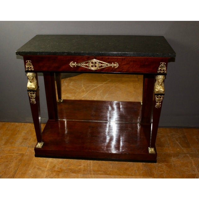 Empire style Egyptian Revival mahogany console table with a mirrored back, a drawer, a Belgian granite marble top,...
