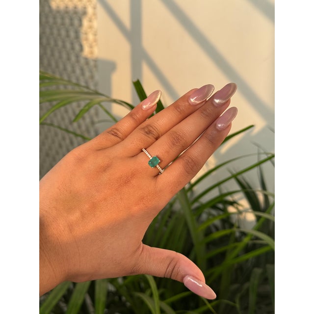 This elegant solitaire engagement ring features a 1.09 carat natural emerald set in 14K yellow gold. The emerald measures...