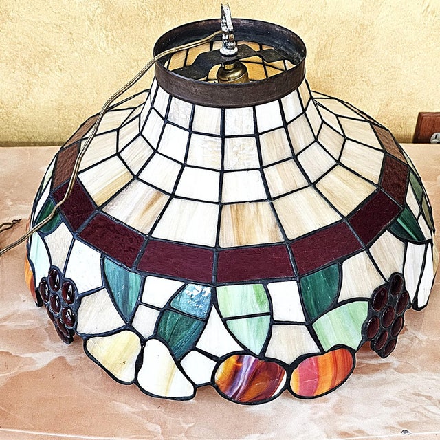 Large Tiffany-style leaded stained-glass pendant shade featuring a colorful fruit-and-leaf border with grapes, pears and...