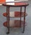 An Early 20th Century mahogany oval three-tiered rolling bar cart with a removable glass-bottom tray, carved and reeded...