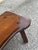 A rustic solid wood bench with an organically shaped live-edge seat, visible wood grain, and four slightly splayed legs....