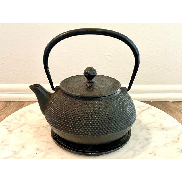 Antique cast Iron Teapot from Japan. Known as a Tetsubin Pot. Includes strainer insert and matching trivet. The teapot is...