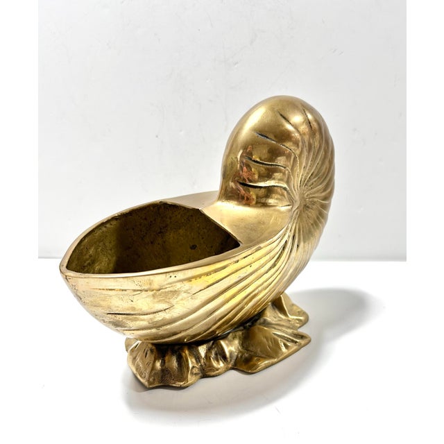 A sculptural brass nautilus shell planter featuring a beautifully spiraled form and radiant golden patina. This Hollywood...