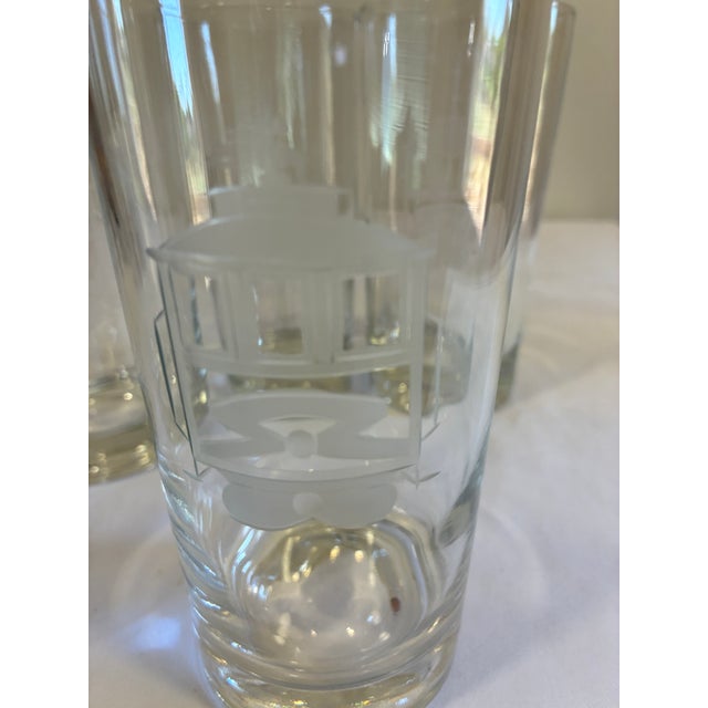 A distinctive set of four vintage clear glass tumblers decorated with etched streetcar or trolley motifs. The frosted...