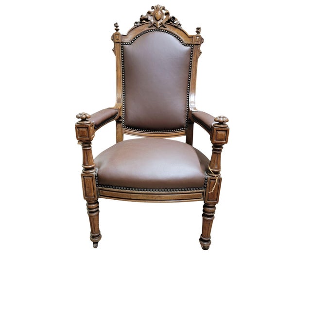 A Victorian Leather Armchair. The top rail with a shield with roses either side and turned finials on top of either end....