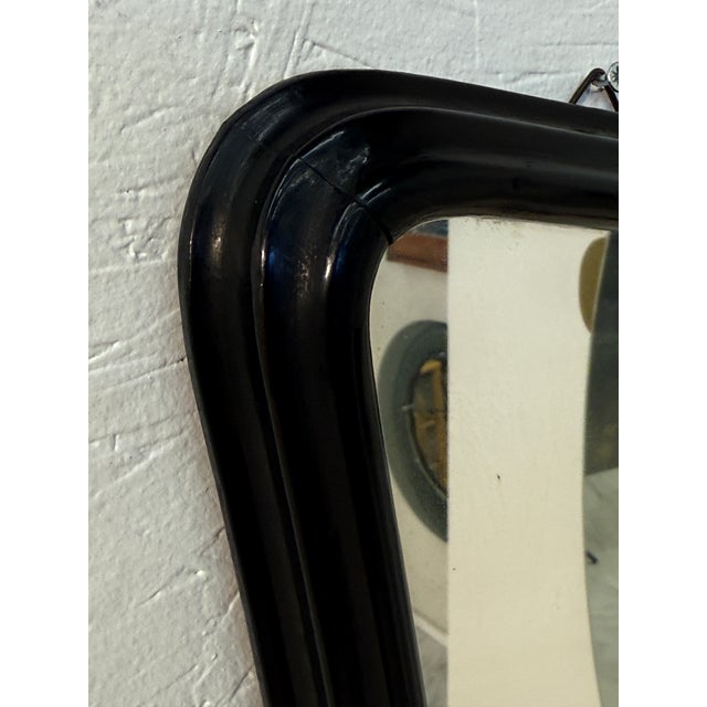 A striking mid-century modern mirror featuring a sculptural black lacquered wooden frame. Its subtly curved, asymmetrical...