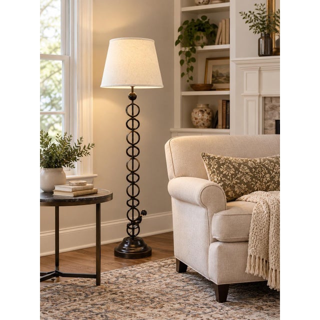 Elegant in its simplicity, this forged iron floor lamp showcases a distinctive off-center ring motif that lends an...
