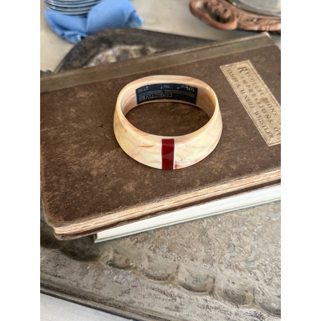 This is a striking vintage bangle bracelet by Monet, featuring a sculptural carved look with soft marbled cream tones...