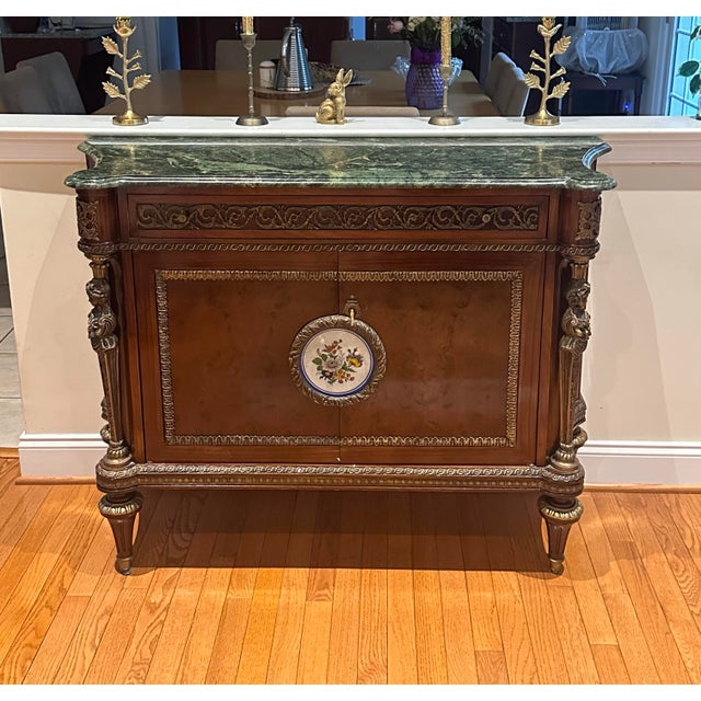 An exceptional antique Louis XVI style marble top cabinet beautifully crafted from solid and burled oak, adorned with...