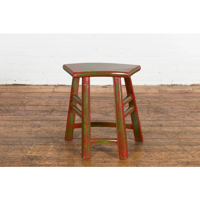 A Japanese late Meiji period red lacquered stool from the early 20th century, with hand painted green accents, semi...